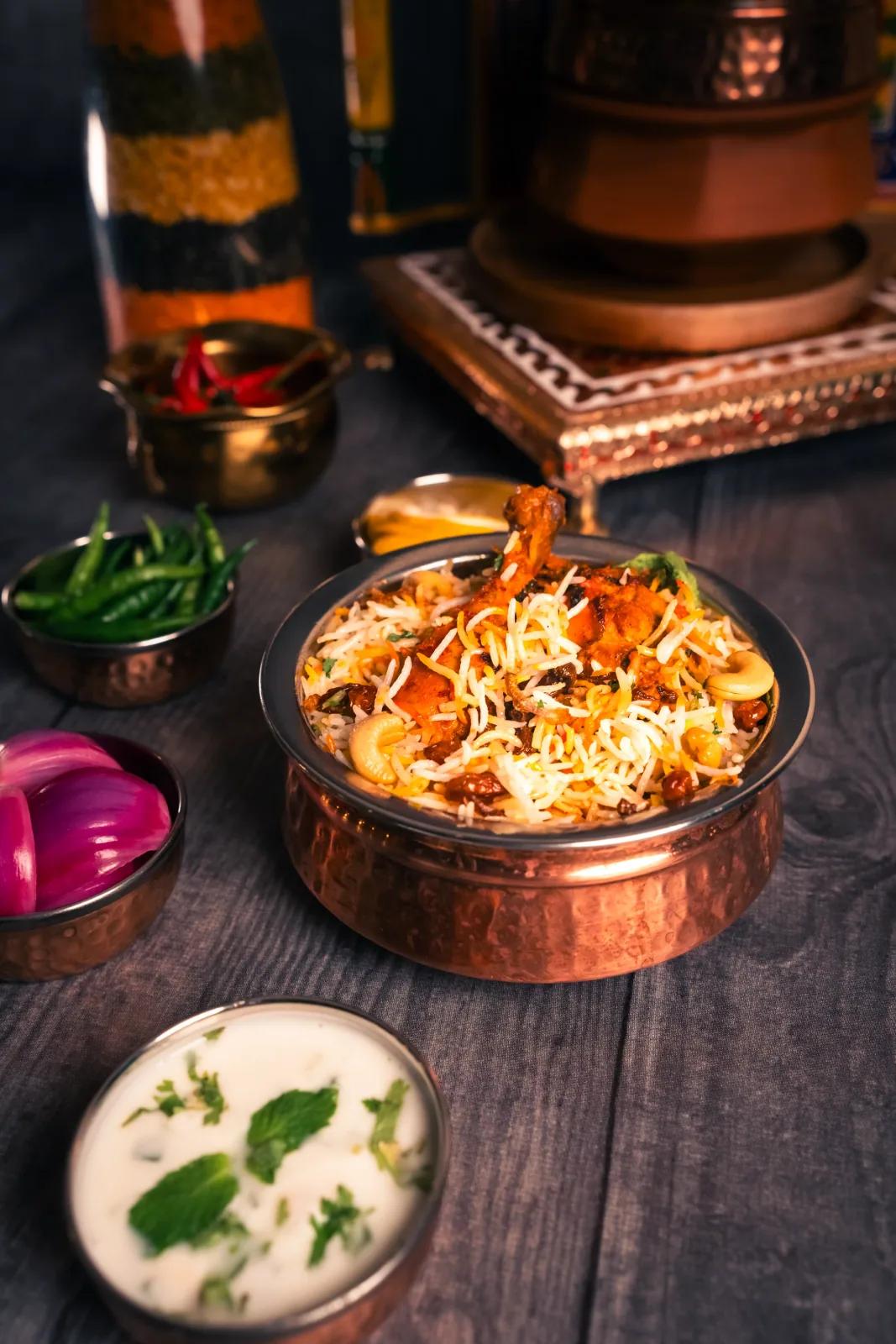 Overhead copper handi biryani with raita and fried onions, food photography by Rahul Chanda, restaurant food photographer India