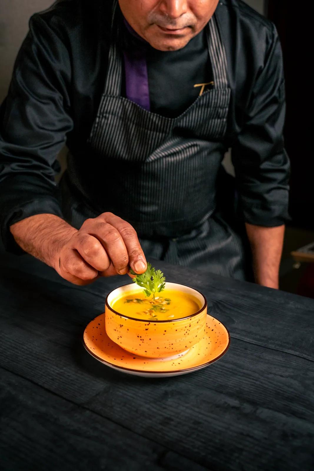 Chef plating a dish in a dark kitchen, behind-the-scenes food photography by Rahul Chanda, Dehradun commercial photographer