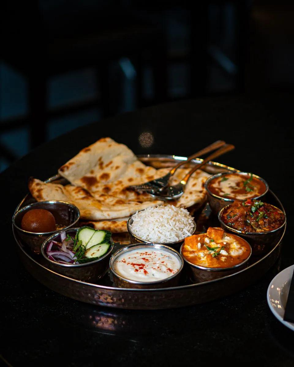 Moody low-lit thali with naan and steel katoris, food photography by Rahul Chanda, Dehradun commercial photographer